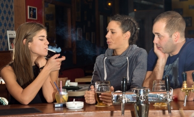 group of three people in bar smoking and drinking